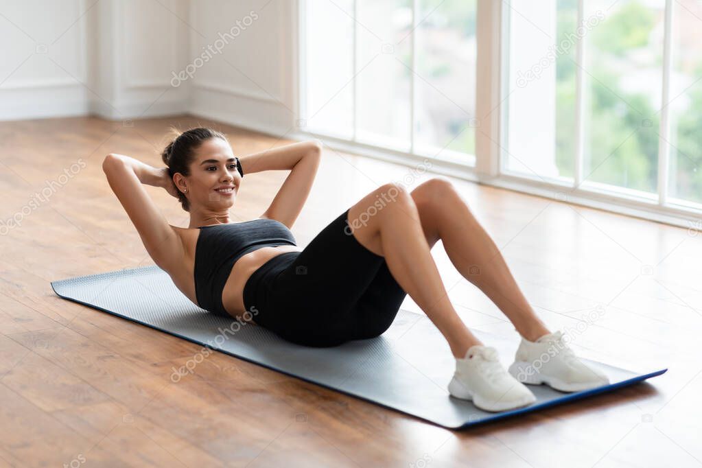 Smiling Young Woman Doing Crunches Exercise On Floor