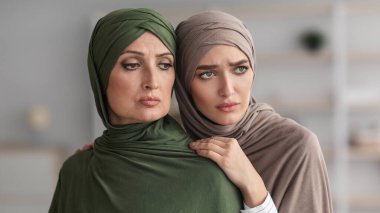 Mutsuz kıdemli Müslüman Kadın ve Yetişkin Kızı Kapalı Kapılar Arasında Kucaklaşıyor