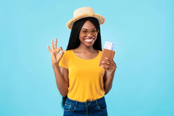 Mujer africana feliz sosteniendo boletos de viaje posando sobre fondo azul — Foto de Stock