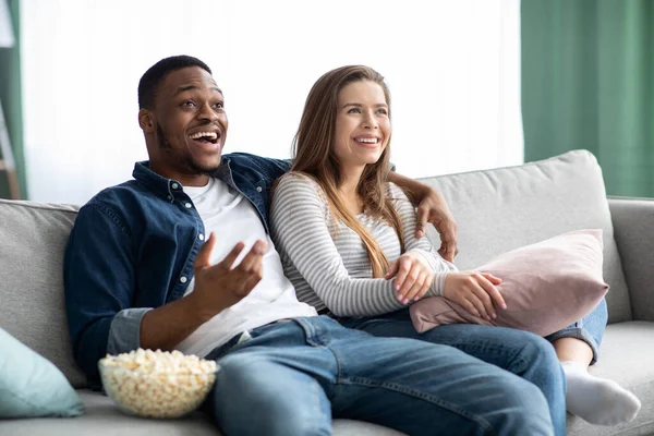 Lazer de fim de semana. Casal interracial assistindo TV e descansando no sofá em casa — Fotografia de Stock