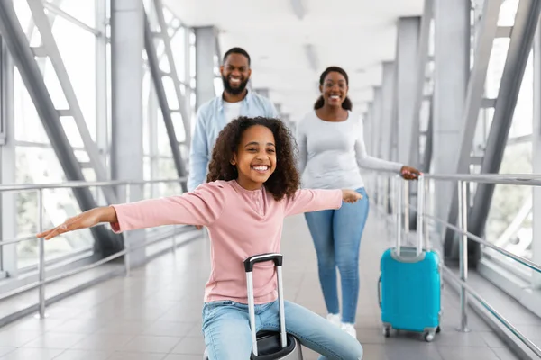 Szczęśliwy czarny rodzina podróżująca z dzieckiem, dziewczyna gra na lotnisku — Zdjęcie stockowe