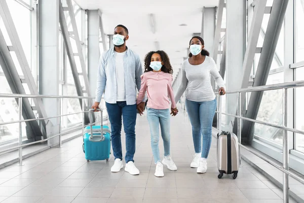 Black family in masks traveling, walking in modern airport