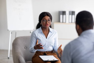 Psikolojik danışmanlık. Profesyonel kadın psikoterapist ofiste genç siyahi bir adamla seans yapıyor.