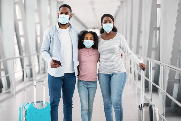 Black family in face masks traveling, posing in modern airport