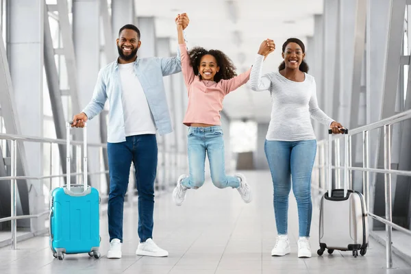 Щаслива чорна сім'я подорожує з дочкою, розважаючись в аеропорту — стокове фото