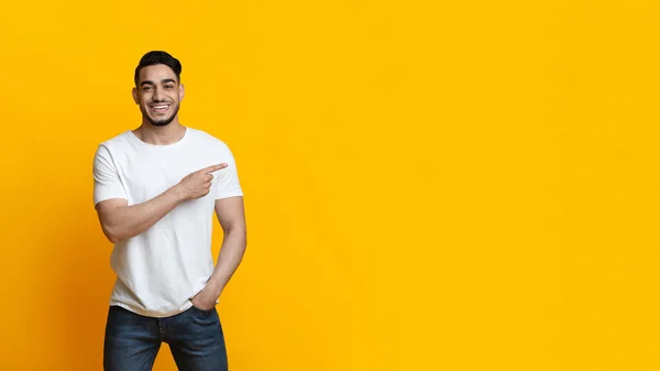 Jovem árabe cara apontando para o espaço de cópia e sorrindo, panorama — Fotografia de Stock