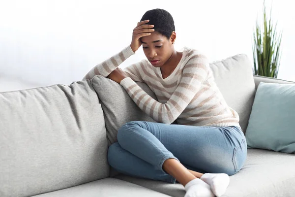 Depresión estacional. Retrato de la triste mujer negra sentada en el sofá en casa —  Fotos de Stock