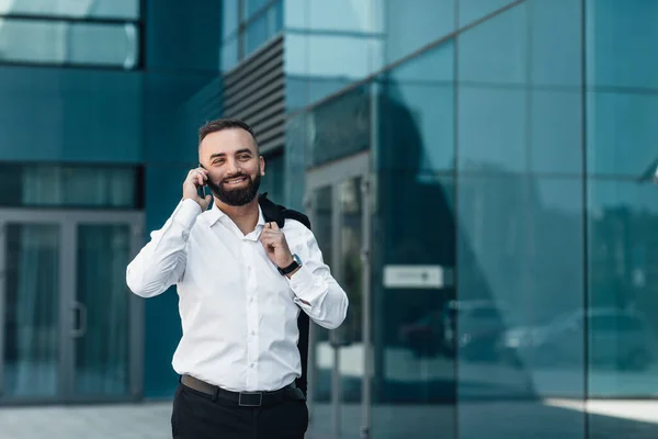 Llamada de negocios. Feliz hombre de negocios confiado charlando en el teléfono inteligente, caminando al aire libre en la ciudad durante el descanso — Foto de Stock