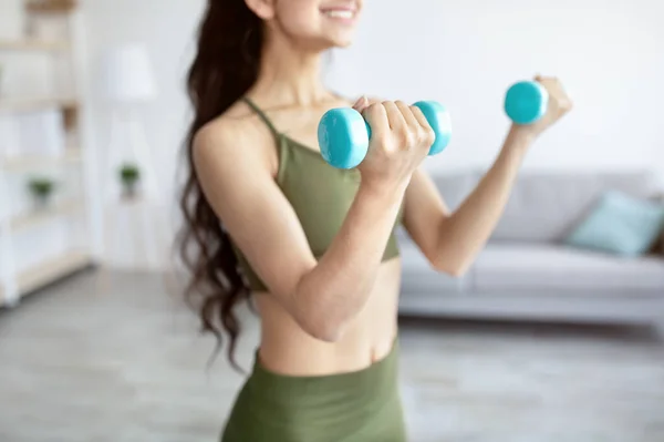Closeup of young Indian lady exercising with dumbbells at home during covid quarantine, selective focus — ストック写真