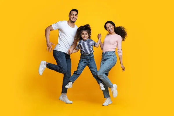 Cheerful Middle Eastern Family Of Three Holding Hands While Jumping In Air — Stock Photo, Image