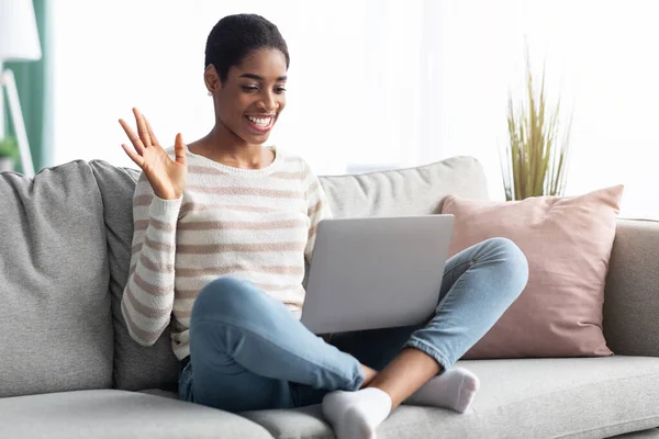 Comunicación en línea. Alegre mujer negra usando el ordenador portátil para videollamada en casa —  Fotos de Stock