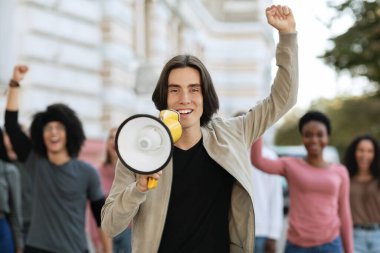 Hoparlörle konuşan neşeli genç adam uluslararası öğrenci grubunu yönetiyor.
