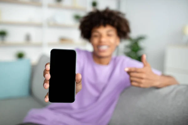 Cool adolescente afroamericano apuntando al teléfono celular con pantalla en blanco en casa, maqueta para aplicación móvil o sitio web —  Fotos de Stock