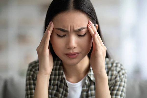 Close-up van jonge aziatische vrouw met hoofdpijn, aanraken van haar tempels — Stockfoto