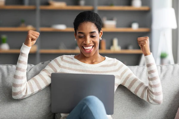 Vincere online. Eccitato afroamericano signora celebrare il successo con il computer portatile a casa — Foto Stock