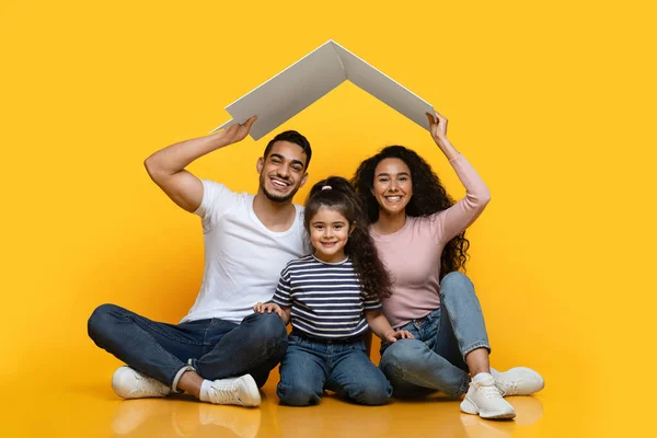 Family Housing. Happy Arab Family Of Three Sitting Under Carton Roof