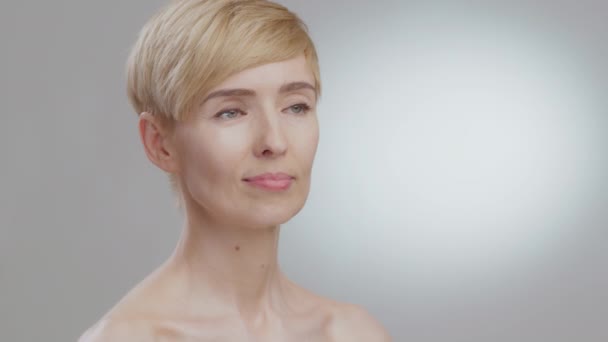 Beauty portret van middelbare leeftijd dame draaien gezicht naar camera en het gevoel opgewonden, zeggen wow, grijze studio achtergrond — Stockvideo