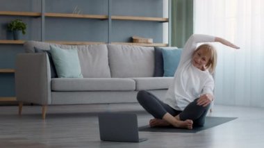 Laptop 'ta egzersiz yapan olgun bir kadın içeride oturuyor.