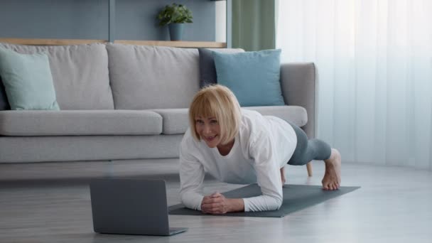 Fit Senior Woman Standing In Plank Ćwiczenia na laptopie w pomieszczeniach — Wideo stockowe