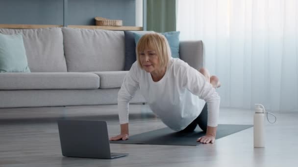 Старша жінка робить Push Ups вправи на ноутбуці вдома — стокове відео