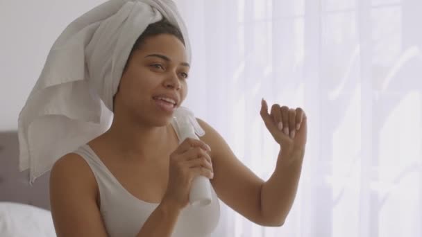 Ung positiv afrikansk amerikansk dam sjunger med lotion flaska på badrummet, dans på badrummet efter morgondusch — Stockvideo
