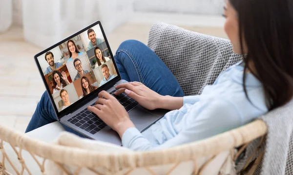 Онлайн-зв'язок. Жінка сидить у кріслі з ноутбуком, маючи груповий відео чат — стокове фото