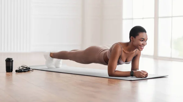 Jovem mulher negra fazendo prancha lateral no tapete — Fotografia de Stock