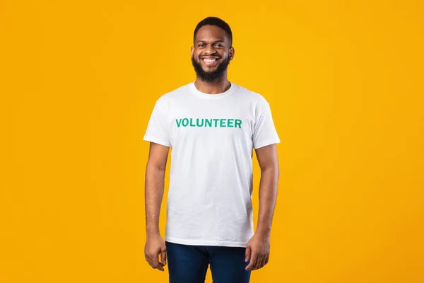 Happy Black Volunteer Guy Standing Wearing Uniform T-Shirt, Yellow Background — Stock Photo, Image