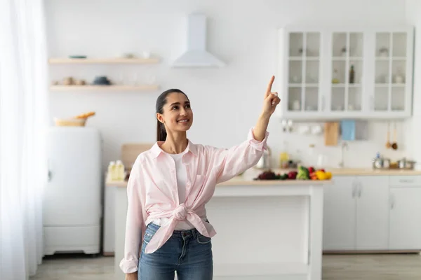 Slim thuis concept. glimlachende vrouw wijzend vinger omhoog in de lucht — Stockfoto