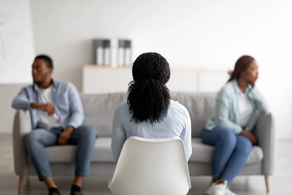 Зворотній погляд психолога, який консультує молоду чорну пару в офісі, допомагає їм вирішити сімейний конфлікт, вибірковий фокус — стокове фото