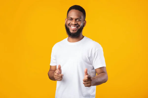 Fröhlicher afroamerikanischer Mann zeigt mit den Fingern auf Kamera, gelber Hintergrund — Stockfoto