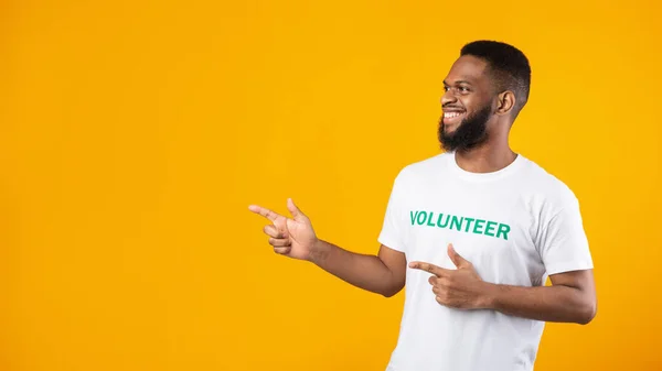 African Volunteer Pointing Fingers Aside At Empty Space, Yellow Background — Stock Photo, Image