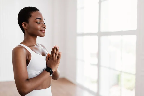 Senhora negra meditando mantendo as mãos juntas em pose de oração — Fotografia de Stock