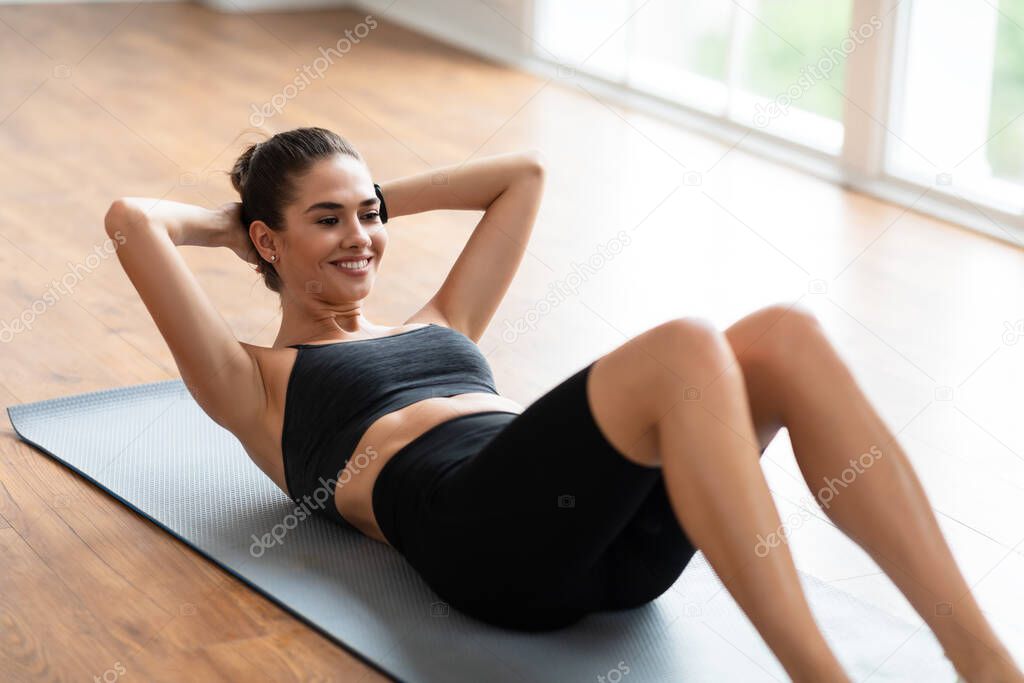 Smiling Young Woman Doing Crunches Exercise On Yoga Mat