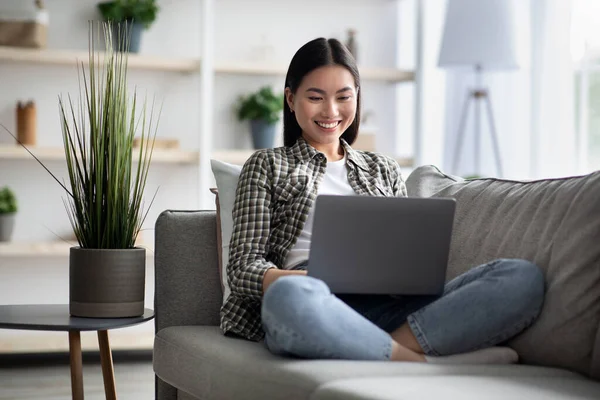 Blij aziatische dame met behulp van gloednieuwe laptop thuis — Stockfoto