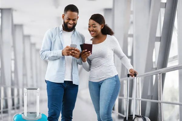 Feliz pareja negra usando el teléfono en el aeropuerto — Foto de Stock
