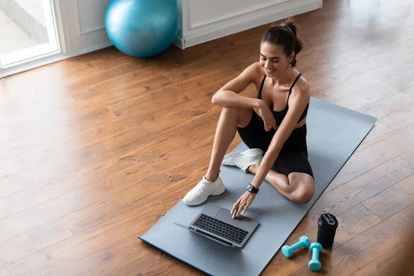Giovane donna sdraiata sul tappetino yoga utilizzando il computer portatile — Foto Stock