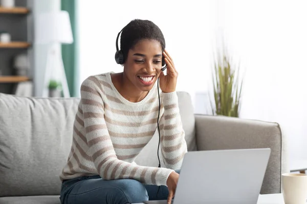 Online onderwijs. Glimlachende zwarte vrouw in headset studie met laptop thuis — Stockfoto