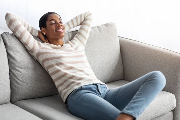 Domowy komfort. Relaks Afroamerykanka pochyla się na kanapie w domu — Zdjęcie stockowe