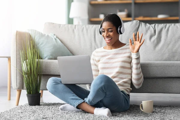 Mujer joven negra en auriculares haciendo videollamada en el ordenador portátil en casa — Foto de Stock