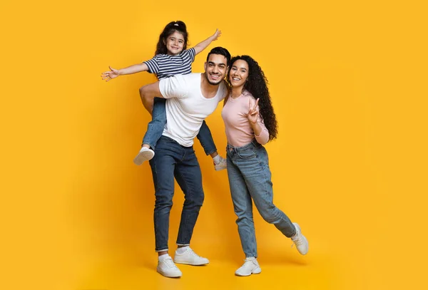 黄色の背景の上に一緒に楽しみを持つ3つの陽気な中東の家族 — ストック写真