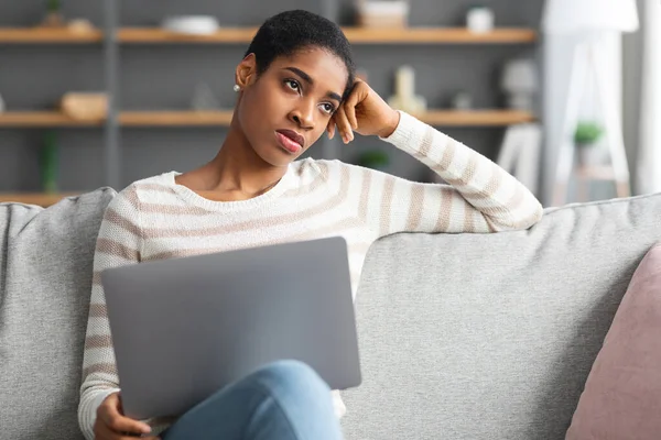 Mangelnde Inspiration. Gelangweilte schwarze Freelancer Dame sitzt mit Laptop auf Couch — Stockfoto
