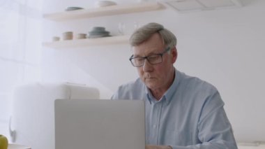 Gig ekonomi konsepti. Yoğunlaştırılmış kıdemli serbest çalışan dizüstü bilgisayar üzerinde çalışıyor, proje yazıyor ve tartışıyorlar