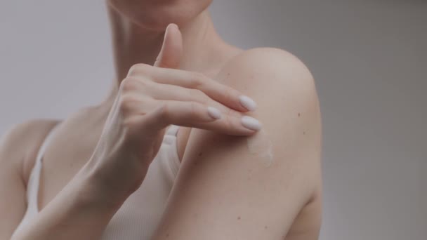 Weibliches Körperverwöhnkonzept. Junge bis zur Unkenntlichkeit kaukasische Frau trägt Feuchtigkeitscreme auf ihre Schulter auf — Stockvideo