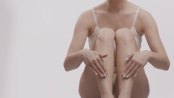 Концепція харчування шкіри. Нерозпізнана біла жінка наносить зволожуючий крем на шкіру сухих ніг, порожній простір — стокове відео