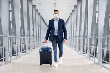 Koruyucu Maskeli Arap İşadamı Havaalanı Terminalinde Bavulla Yürüyor