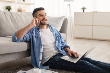 Gülümseyen Yahudi adam evde çalışıyor ve telefonla konuşuyor.