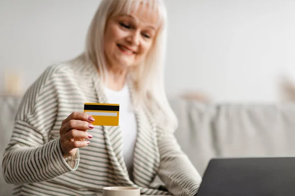 Усміхнена зріла жінка використовує кредитну картку вдома — стокове фото
