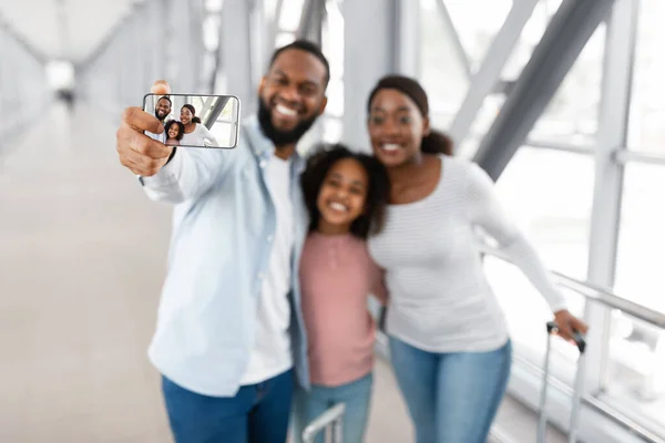 African American family traveling, taking selfie on cellphone in airport
