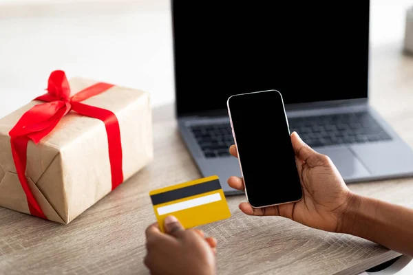 Detailní záběr černošky pomocí moderního smartphonu, notebooku a kreditní karty nakupovat dárky on-line z domova, mockup — Stock fotografie